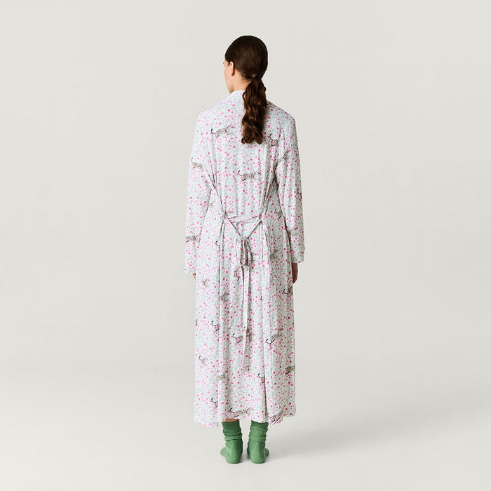 Woman wearing a long floral robe on a plain background