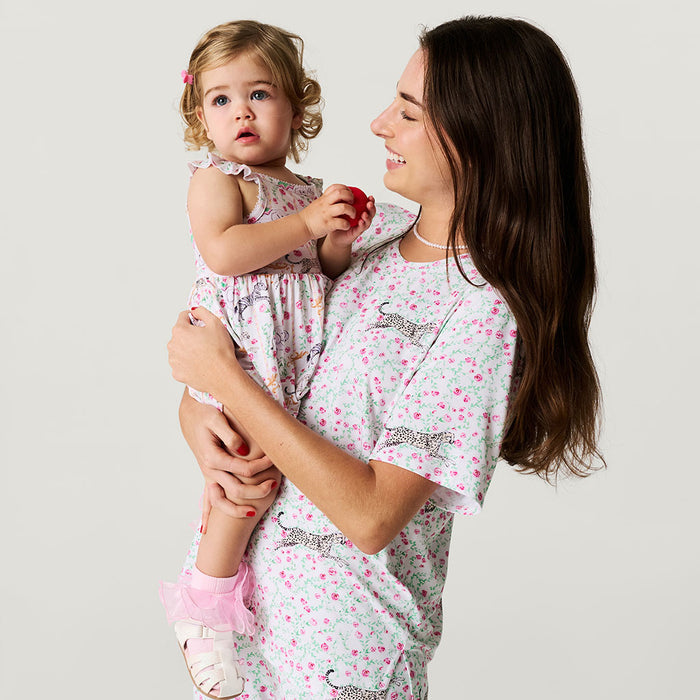 Woman holding a child wearing matching pajamas with animal prints on a plain background