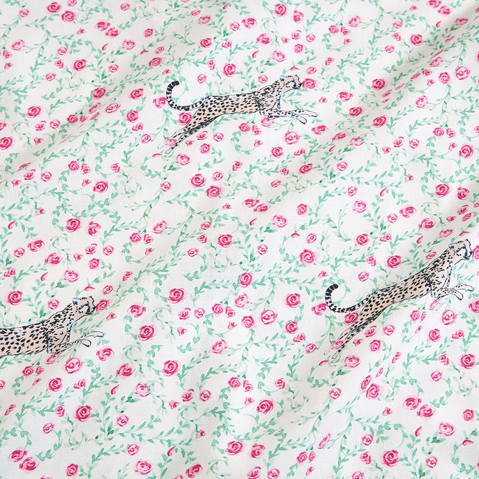 Fabric with a pattern of pink roses and leopards on a white background