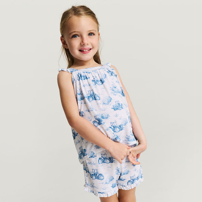 Young girl wearing a white sleeveless top and shorts with blue vintage car pattern on a light gray background
