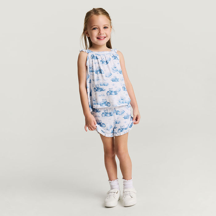 Young girl wearing a blue and white patterned short set on a light gray background