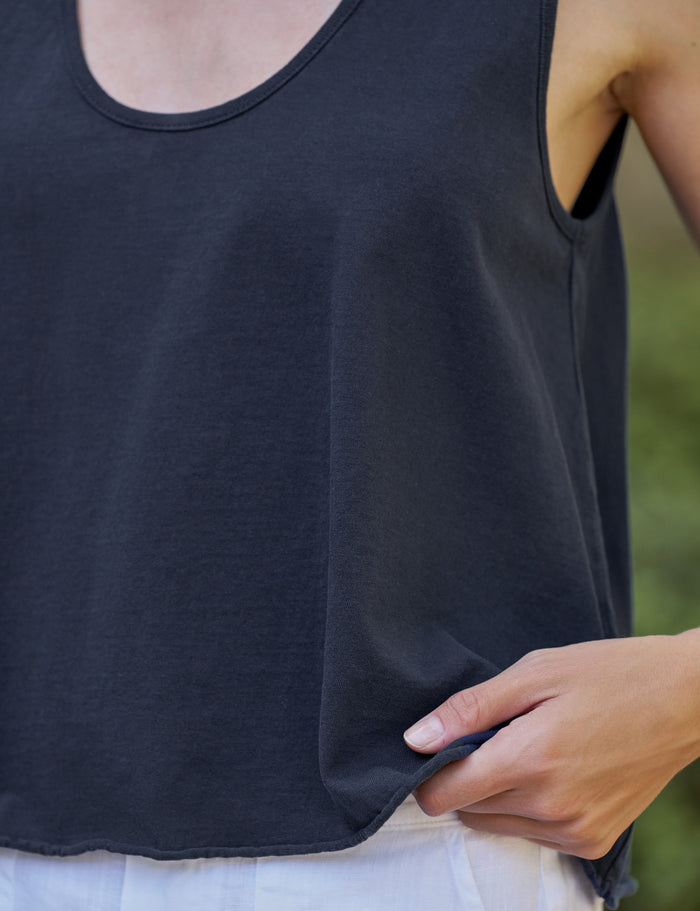 Person wearing a navy tank top with a blurred green background