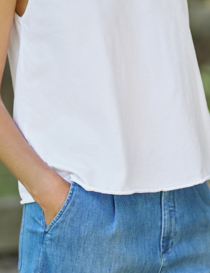 Person wearing a white top and blue jeans with a blurred background