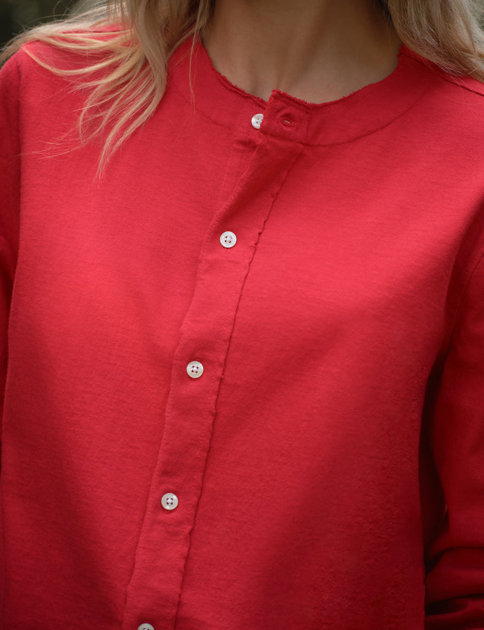 Close-up of a red cardigan worn by a person with blonde hair.
