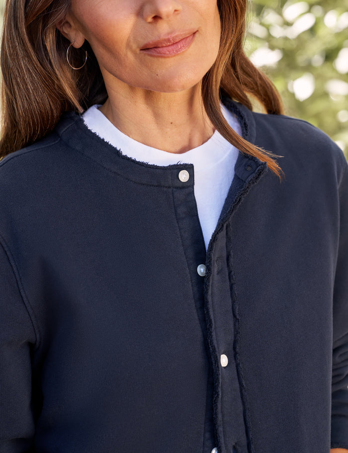 Person wearing a navy blue jacket with a blurred green background