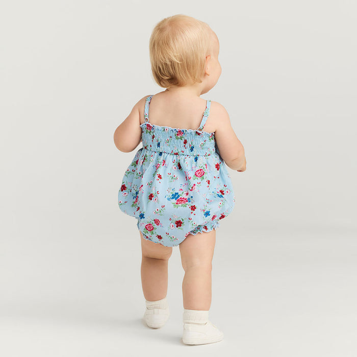 Baby wearing a floral romper on a plain background