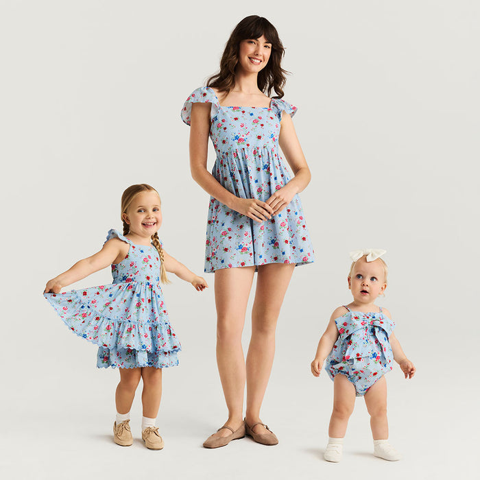 Woman and two children wearing matching blue floral outfits on a plain background
