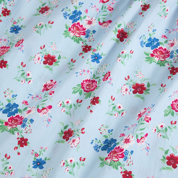 Floral patterned fabric with red, blue, and pink flowers on a light blue background