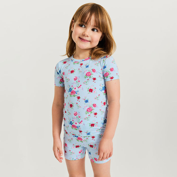 Child wearing a light blue floral pajama set on a plain background