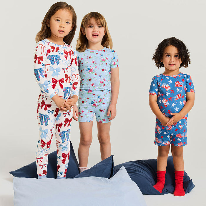 Three children wearing colorful pajamas on a plain background