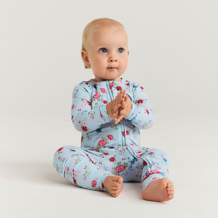 Baby wearing a floral onesie on a plain background