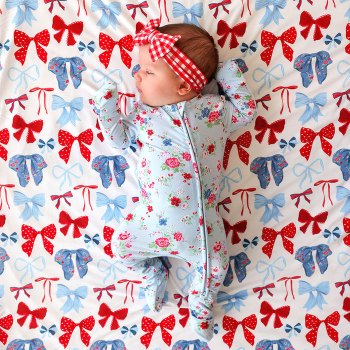 Baby lying on a blanket with red, white, and blue bow pattern