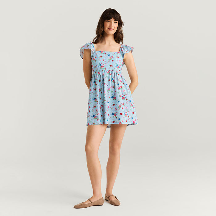 Woman wearing a light blue floral dress on a plain background