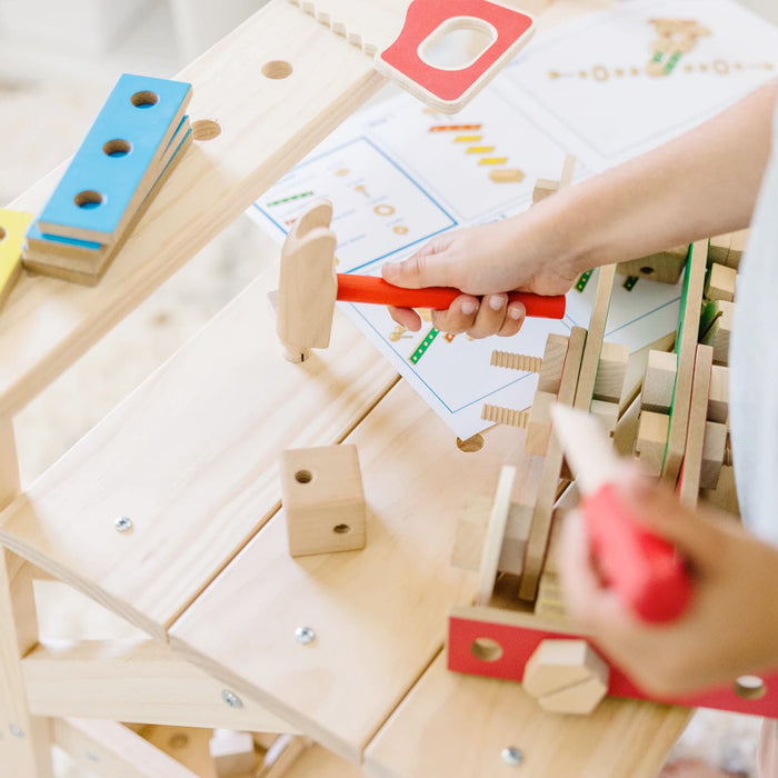 Child playing with a wooden hammer on a workbench toy