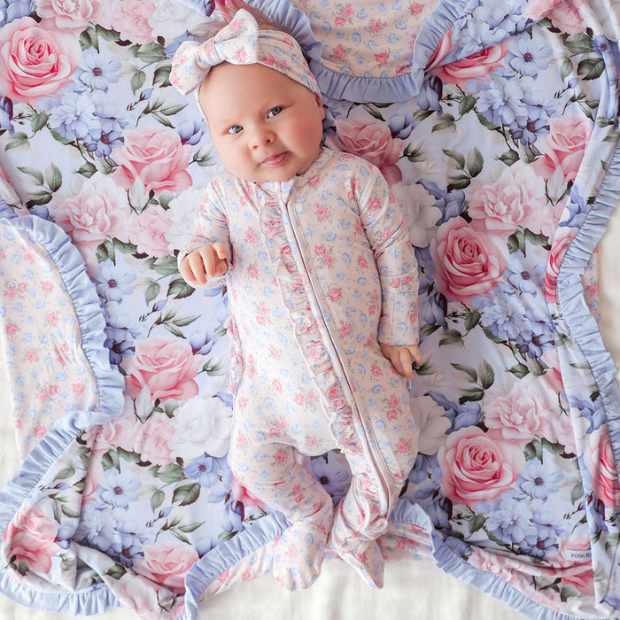 Baby in floral one piece lying on a floral blanket