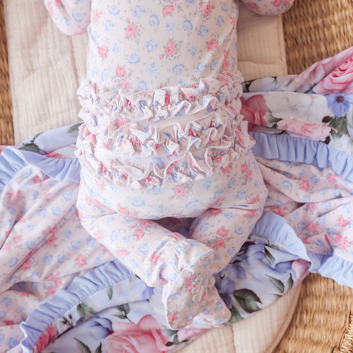 Floral patterned baby outfit with ruffles on a wooden surface