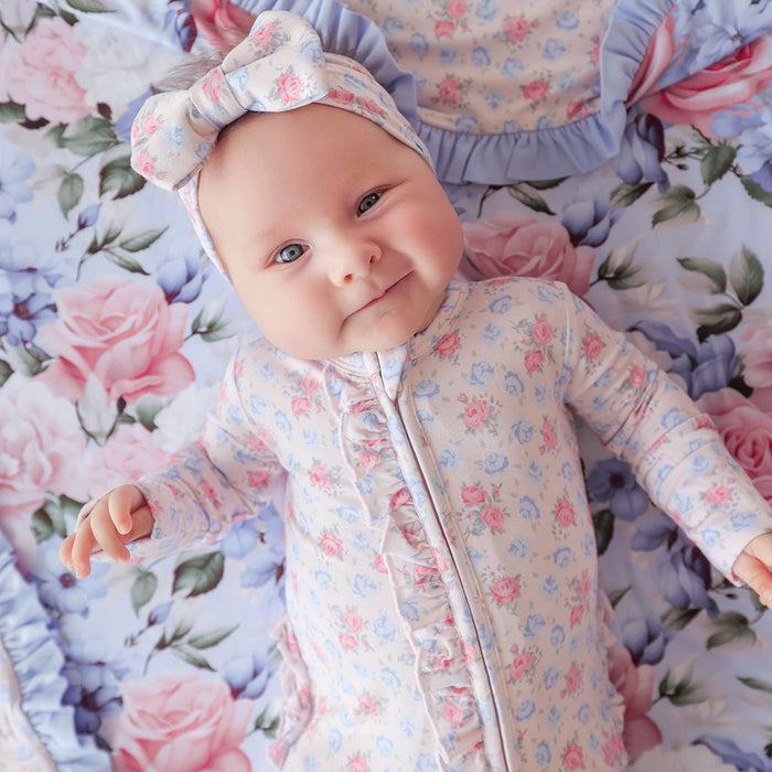 Baby in floral outfit and headband on a floral blanket