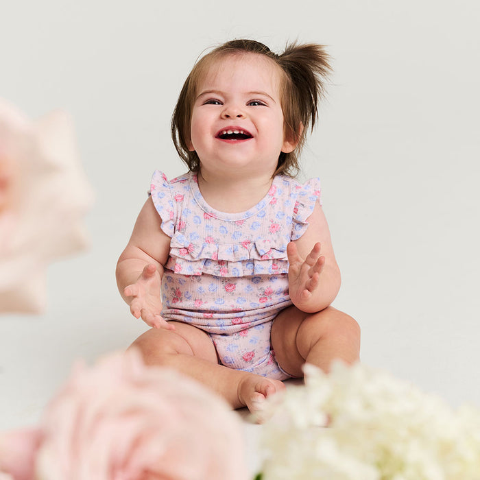 Child wearing a floral outfit with a plain background