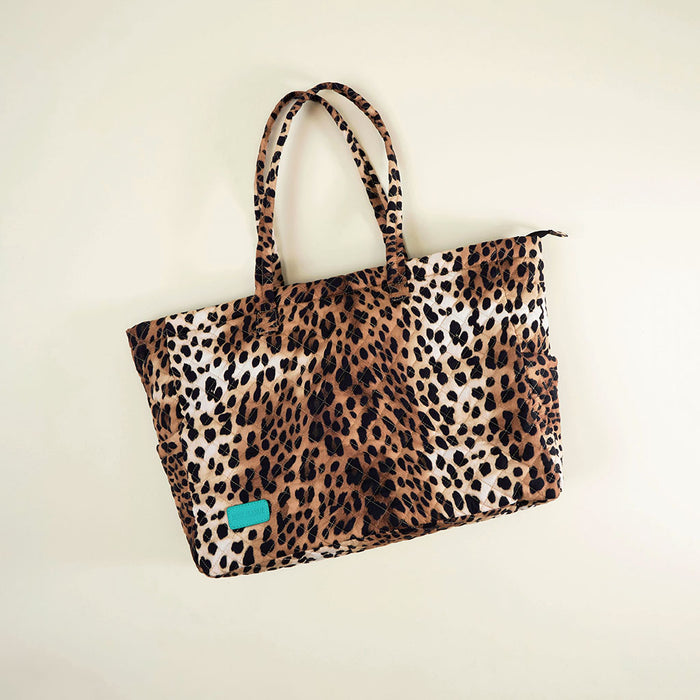 Leopard print tote bag with a blue tag on a beige background