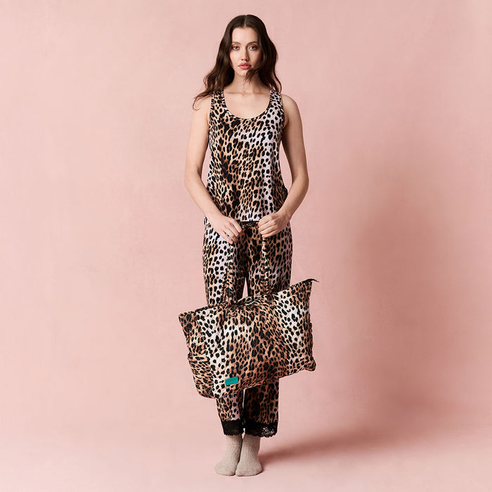 Woman wearing matching  leopard print outfit holding the leopard tote bag on a pink background