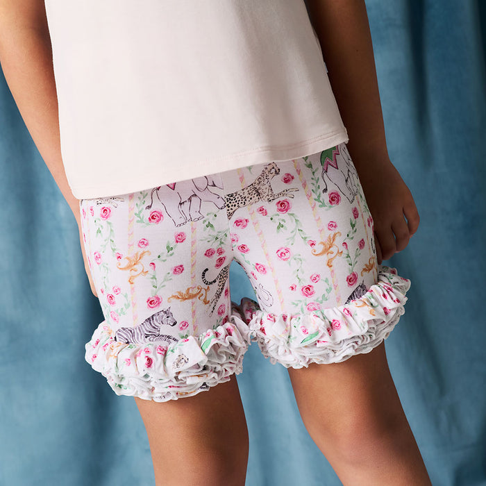 Child wearing floral shorts with ruffles on a blue background