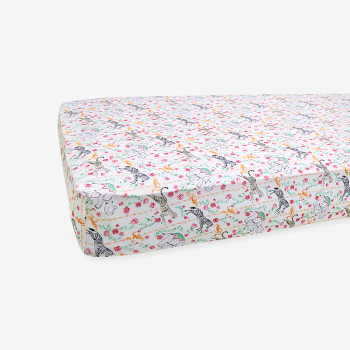 Floral and animal patterned crib sheet on a white background