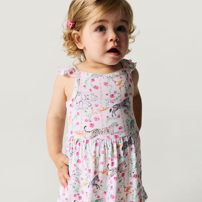 Child wearing a floral dress with animal prints on a plain background