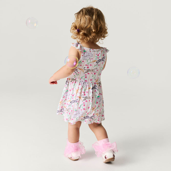 Child wearing a floral dress with animal prints on a plain background