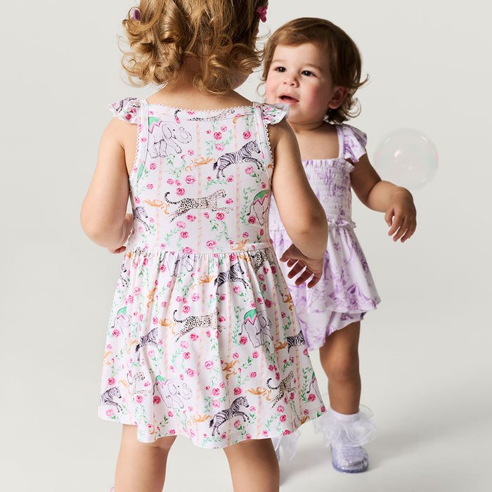 Two young girls wearing floral dresses on a plain background