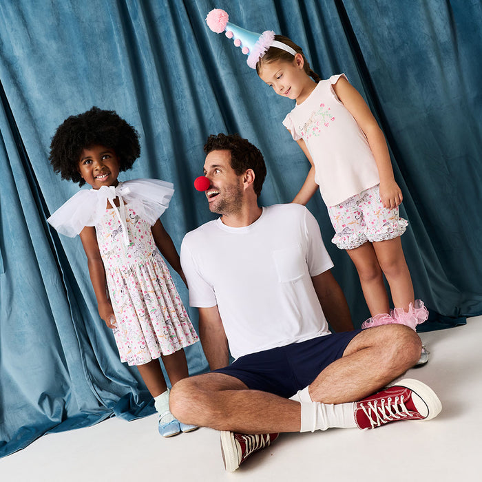 Man with two young girls in front of a blue curtain
