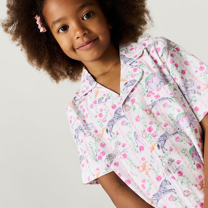 Child wearing a patterned shirt with animals and flowers on a plain background