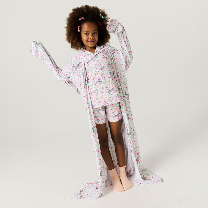 Young girl wearing a floral pajama set with long sleeves and matching shorts on a plain background