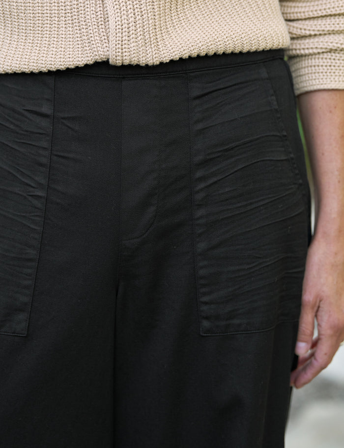 Close-up of black pants worn with a beige sweater.