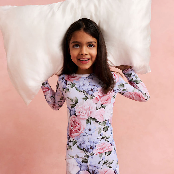 Young girl wearing a floral onesie with a pink background