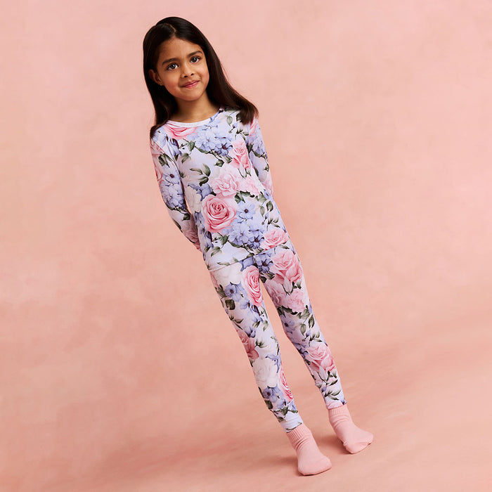 Young girl wearing a floral pajama set on a pink background
