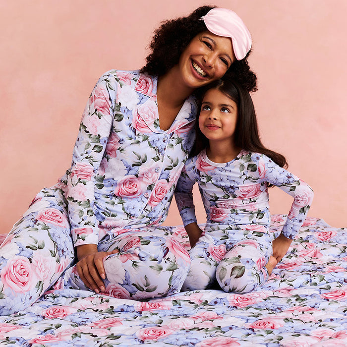 Woman and child wearing matching floral pajamas against a pink background