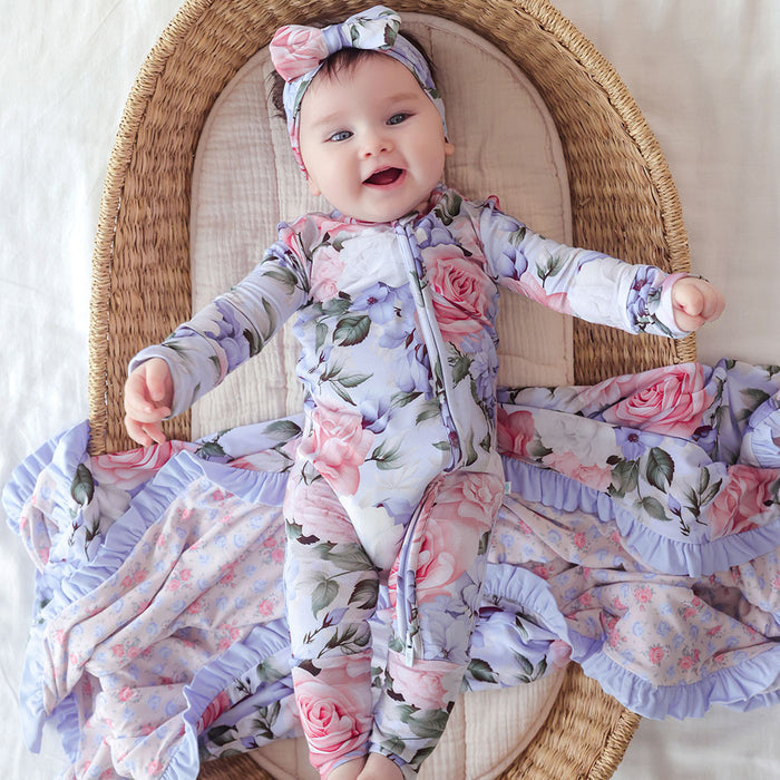Baby in floral outfit and headband lying on a woven basket