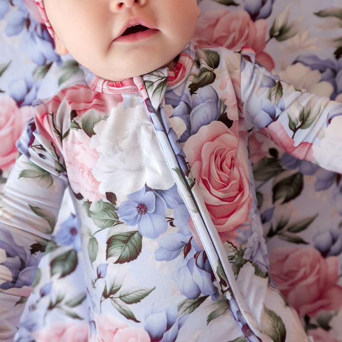 Baby wearing a floral onesie with a floral background