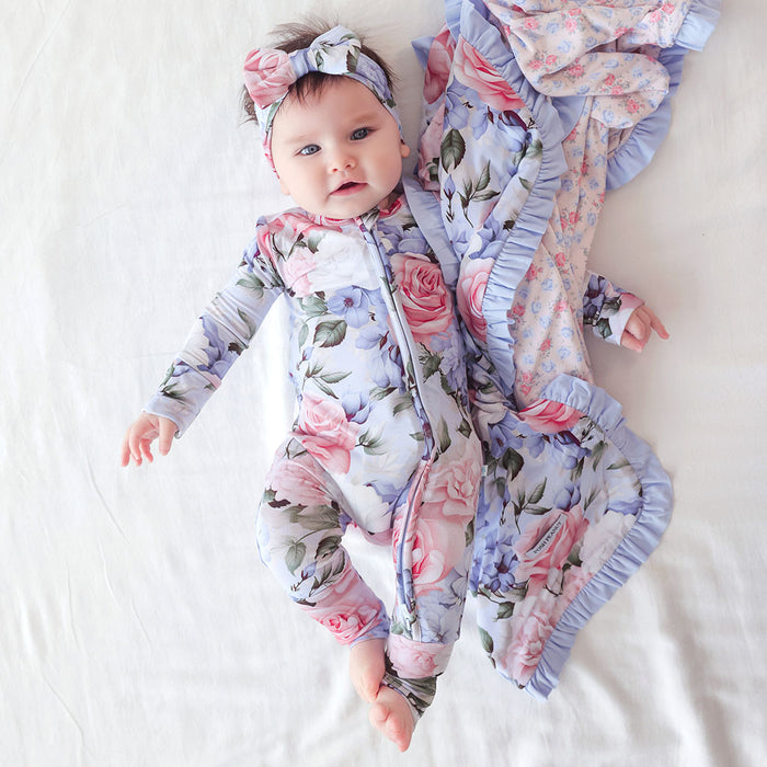 Baby in a floral outfit and swaddle on a white background