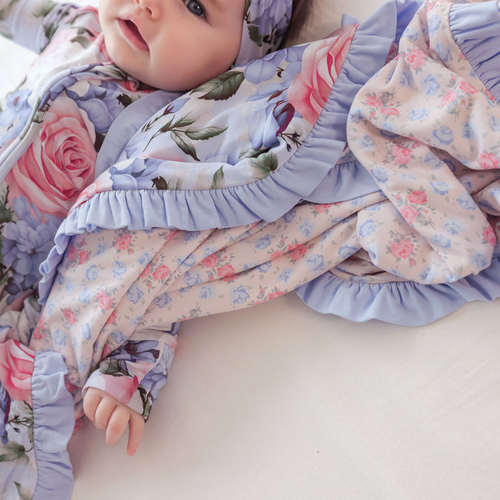 Baby in a floral outfit with ruffled details on a white background