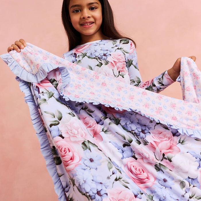 Young girl holding a floral blanket against a pink background