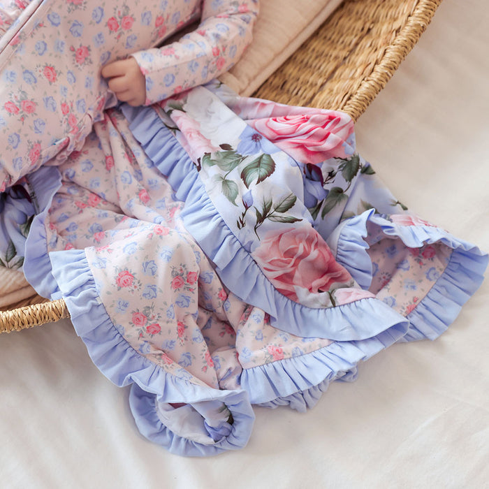 Floral and ruffled fabric with pink roses and blue lace in a wicker basket.