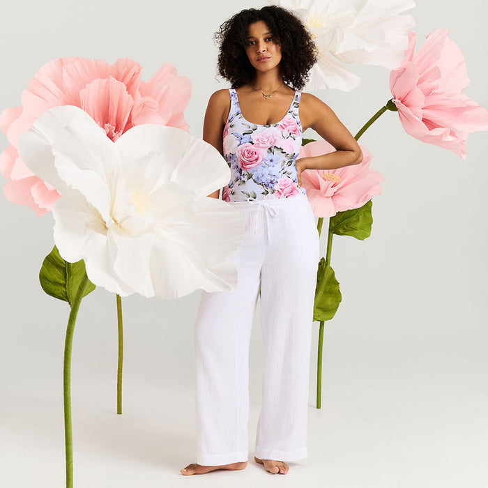 Woman posing with large pink and white flowers on a plain background