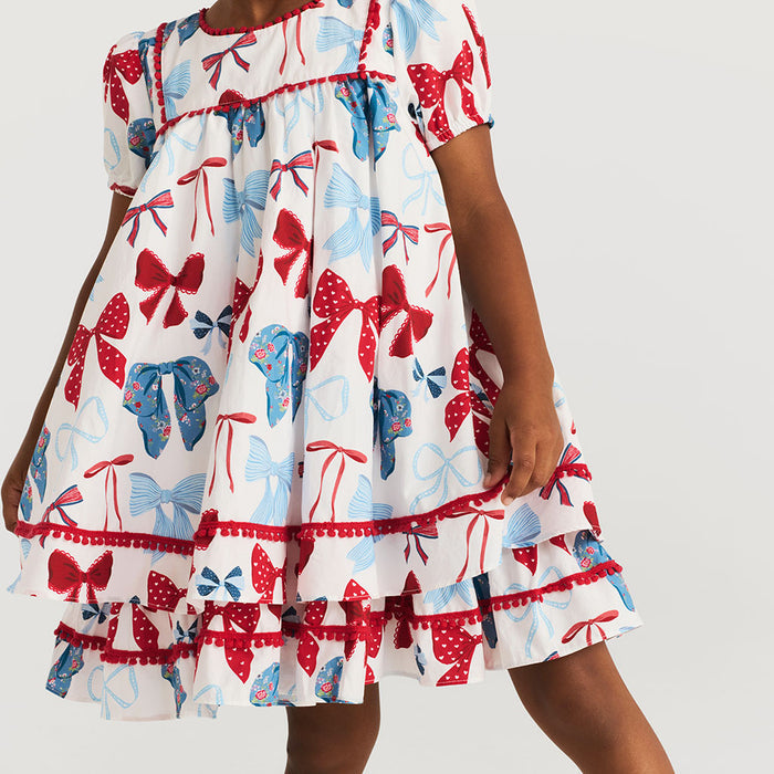 Dress with red, blue, and white bow pattern on a plain background