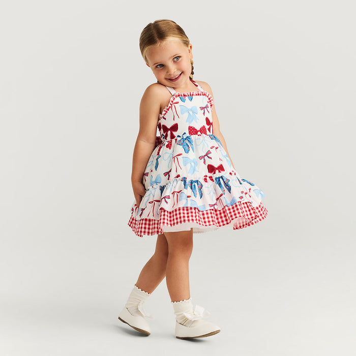 Young girl wearing a dress with bow pattern on a plain background