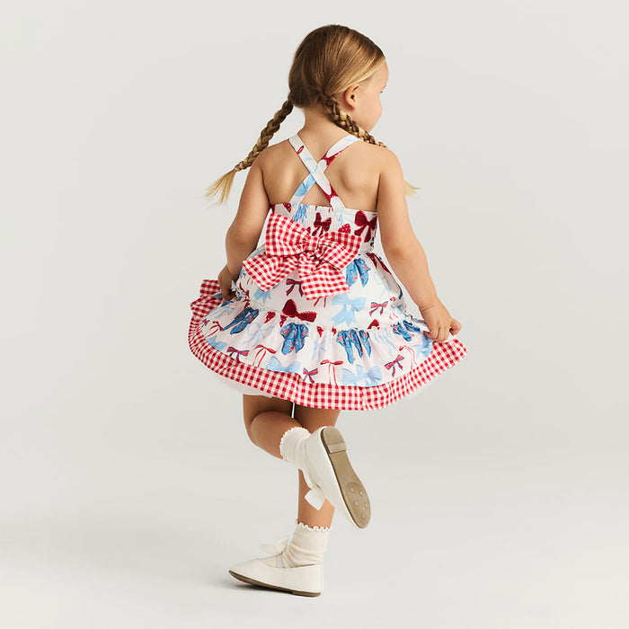 Young girl wearing a red and white checkered dress with blue patterns on a light gray background