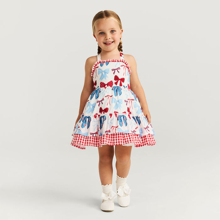Young girl wearing a dress with bow pattern on a plain background