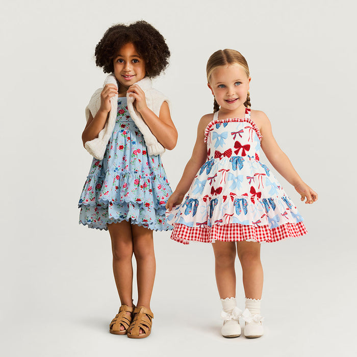 Two young girls wearing colorful dresses on a plain background