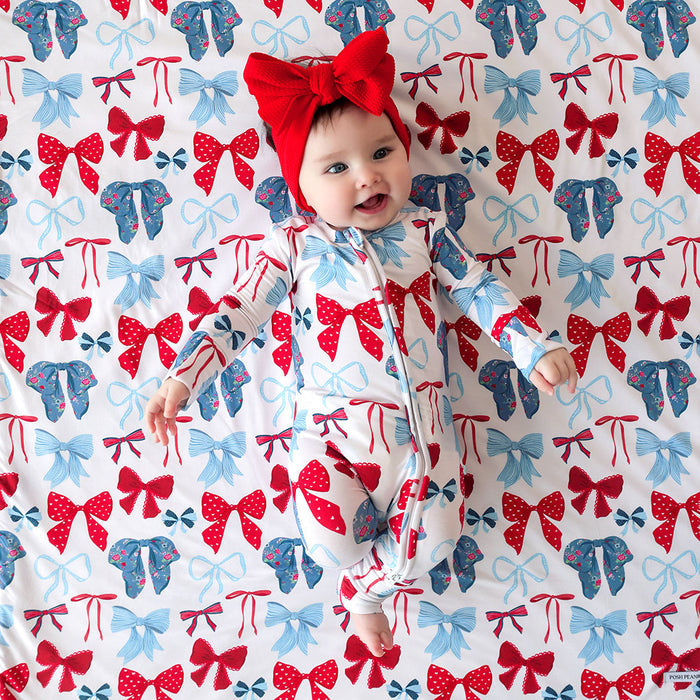 Baby in a red and blue bow patterned outfit on a matching background