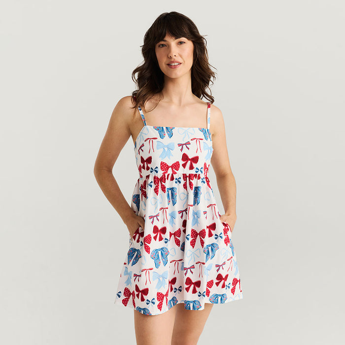 Woman wearing a dress with a colorful bow pattern on a plain background